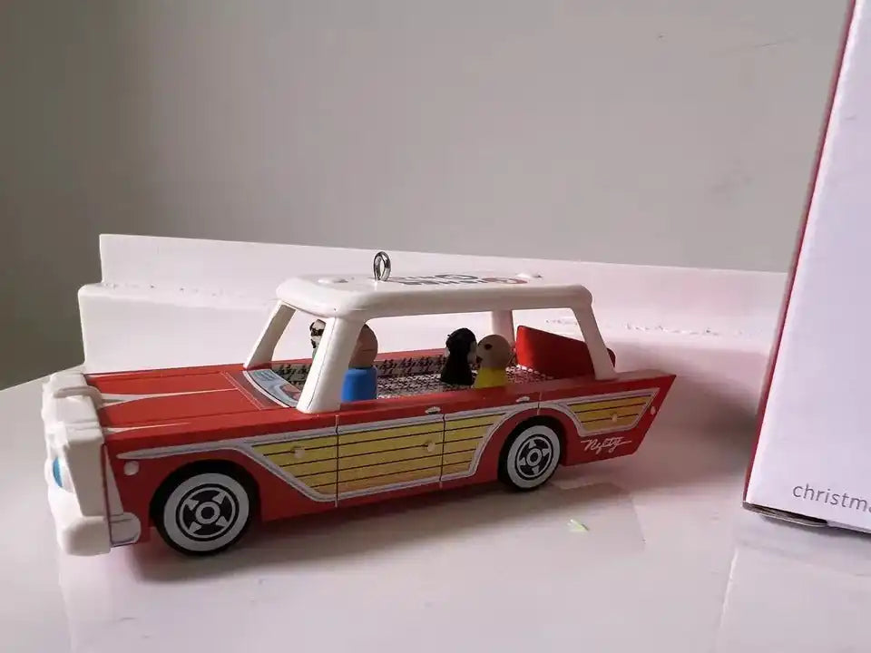 Red, yellow, and white station wagon ornament with two passenger figures